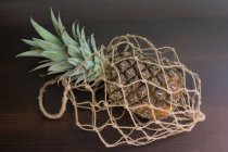 Pineapple in a mesh bag, closeup view — Stock Photo