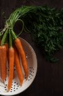 Fresh carrots in a colander, closeup view — Stock Photo