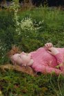 Fille souriante couchée sur l'herbe avec ses cheveux écartés — Photo de stock