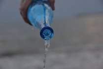 Main humaine versant une bouteille d'eau — Photo de stock