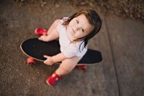 Visão aérea de uma menina sentada em um skate — Fotografia de Stock