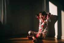 Девушка, сидящая на полу в пижаме и смеющаяся — стоковое фото