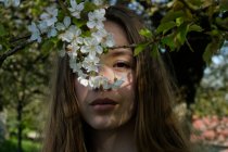 Портрет дівчини-підлітка, що стоїть під вишневим розквітлим деревом — стокове фото