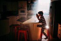 Ragazzo seduto in cucina a mangiare la sua colazione in luce del mattino — Foto stock