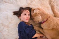 Girl lying on floor playing with her golden retriever dog — Stock Photo