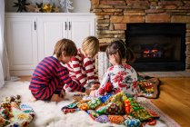 Three children sitting on the floor playing a board game — Stock Photo