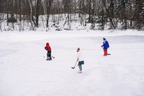 Drei Kinder spielen Eishockey — Stockfoto