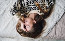 Jeune femme souriante couchée sur le lit — Photo de stock