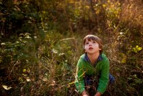 Nahaufnahme Porträt eines Jungen, der auf einem Feld sitzt — Stockfoto