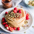 Stack of Pancakes with chocolate sauce, chopped pistachio nuts and strawberries — Stock Photo