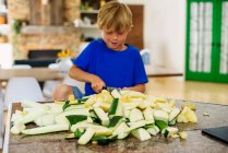 Junge steht in Küche und hackt Kürbis — Stockfoto