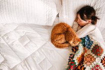 Young girl sleeping on bed with cat — Stock Photo