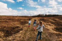Happy kids at autumn field under cloudy sky — Stock Photo