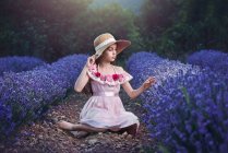 Дівчина в солом'яному капелюсі сидить у лавандовому полі — стокове фото