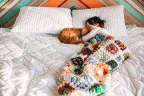 Молода дівчина спить на ліжку з кішкою — стокове фото