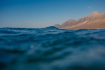 Hermosa vista de las montañas sobre las olas del mar - foto de stock
