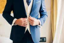 Cropped shot of groom buttoning suit — Stock Photo