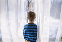 Junge schaut aus dem Fenster — Stockfoto