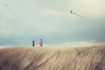Couple debout sur une colline volant un cerf-volant — Photo de stock
