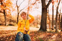 Giovane ragazzo giocando sul cortile altalena di legno — Foto stock