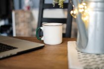 Nahaufnahme der Tasse neben einem Laptop auf einem Schreibtisch — Stockfoto