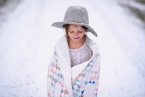 Молода дівчина з капелюхом зовні, загорнута в ковдру — стокове фото