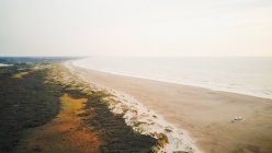 Bella vista sul mare e sulla spiaggia sabbiosa la mattina nebbiosa — Foto stock