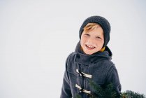 Портрет усміхненого хлопчика, що стоїть у снігу — стокове фото