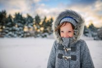Портрет усміхненої дівчини, що стоїть в снігу в теплому пальто — стокове фото