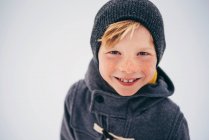 Retrato de un niño sonriente sosteniendo una corona de Navidad - foto de stock