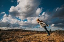 Вид хлопчика на осіннє поле під хмарним небом — стокове фото