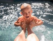 Boy in a swimming pool holding his mother's feet, Orange County, California, United States — Stock Photo