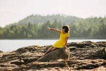 Young girl playing on rocks by a lake — Stock Photo