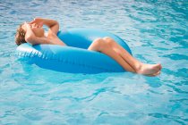 Ragazzo galleggiante in una piscina su un anello di gomma gonfiabile — Foto stock
