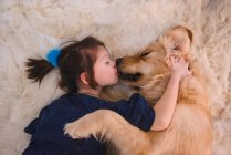 Девушка лежит на полу и целует свою золотую собаку-ретривер — стоковое фото