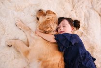 Fille dormir sur un tapis avec son chien golden retriever — Photo de stock