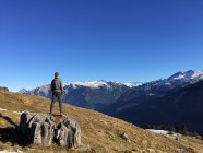 Niño de pie sobre rocas mirando a la vista, Braunwald, Glarus, Suiza - foto de stock
