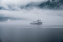 Лодки, плывущие по течению в тумане, Море из Ромсдаля, Норвегия — стоковое фото