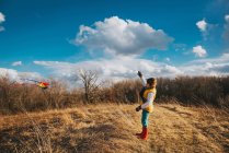 Вид на хлопчика з повітряним змієм на осінньому полі під хмарним небом — стокове фото