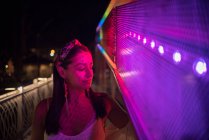 Donna in piedi in strada accanto a luci al neon, Bosnia-Erzegovina — Foto stock