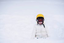 Portrait of a girl sitting in snow wearing a skiing helmet — Stock Photo