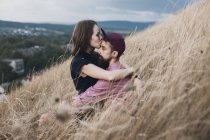 Woman sitting in a field kissing her boyfriend — Stock Photo