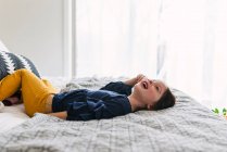 Girl lying on her bed laughing — Stock Photo