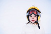 Portrait d'une fille assise dans la neige portant un casque de ski — Photo de stock