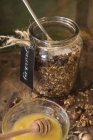 Pot de granola avec miel sur table rustique en bois — Photo de stock
