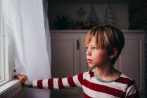 Rapaz a olhar pela janela em casa — Fotografia de Stock