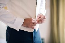 Cropped shot of groom buttoning shirt — Stock Photo