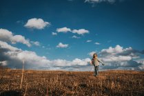 View of boy at autumn field under cloudy sky — Stock Photo