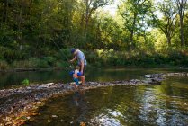 Uomo che pesca in un fiume con suo figlio — Foto stock