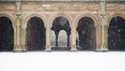 Считается сердцем Центрального парка Нью-Йорка, это Бетесда Террас. Женщина идет через арки и из снега. — стоковое фото